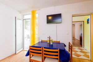 a dining room with a table and a tv on the wall at Apartments Glavor in Drače