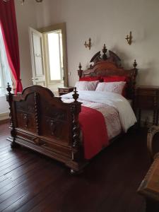 加來的住宿－B & B Les Secrets des Loges，一间卧室配有一张大木床,铺有红色和白色的床单。