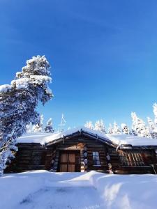 uma cabana de madeira na neve em Saarikejo Huskylodge em Saariselka