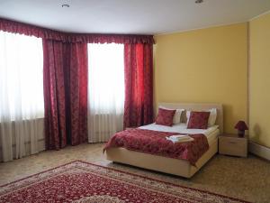 Schlafzimmer mit einem großen Bett und roten Vorhängen in der Unterkunft Orion Inn in Iwanowo