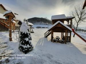 une cour enneigée avec un kiosque dans l'établissement Pensiunea Valea Branzei, à Năneşti