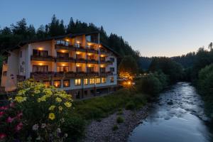 a hotel with a river in the foreground at Sackmanns Wanderhotel Löwen in Baiersbronn