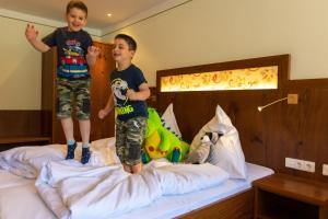 two young boys jumping on top of a bed at Sackmann Wanderhotel in Baiersbronn
