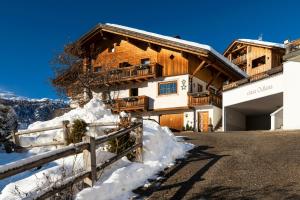 a wooden house with snow in front of it at Ciasa Odlana in San Cassiano