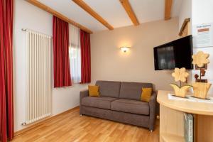 een woonkamer met een bank en een tv bij Ciasa Odlana in San Cassiano