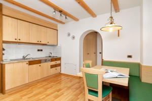 een keuken met houten kasten en een houten tafel en stoelen bij Ciasa Odlana in San Cassiano