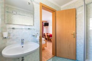 a bathroom with a white sink and a room at Apartments Puntin in San Cassiano