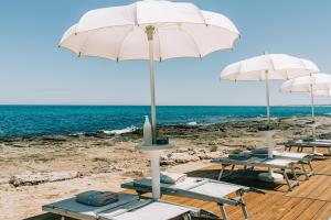 a group of chairs and umbrellas on a beach at Torre Cintola Greenblu Sea Emotions in Monopoli