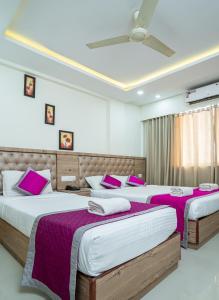 a bedroom with two beds with purple and white sheets at Nexstay Crystal Residency in Kozhikode