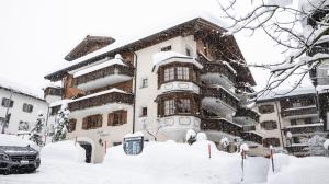 um edifício coberto de neve em frente a um edifício em Wunderstay Alpine 3 Chic Studio Central Location em Klosters Serneus