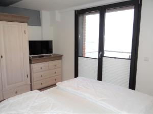 Schlafzimmer mit einem Bett, einem TV und einem Fenster in der Unterkunft Speicher Residenz Barth E4 App 4 in Barth