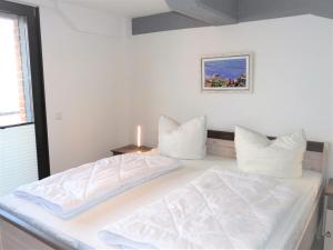 ein weißes Schlafzimmer mit einem Bett mit weißer Bettwäsche und Kissen in der Unterkunft Speicher Residenz Barth E4 App 4 in Barth