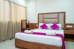 a bedroom with a large bed with pink pillows at Nexstay Crystal Residency in Kozhikode