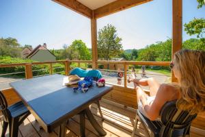 une femme assise à une table sur une terrasse couverte dans l'établissement Domaine du Surgié, à Figeac