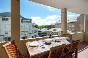 una mesa de madera con sillas en un balcón con vistas en Jenatt Apartments Salamanca, en Hobart