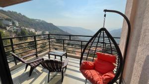 a porch with a swing and a table on a balcony at Belle-Vue Holiday Homes in Panchgani