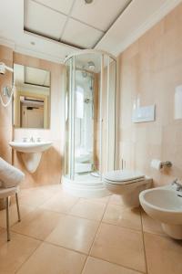 a bathroom with two sinks a toilet and a shower at Argonauti Greenblu Resort in Marina di Pisticci