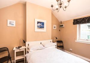 a bedroom with a bed and chairs and a window at Summerside Cottage in Gullane