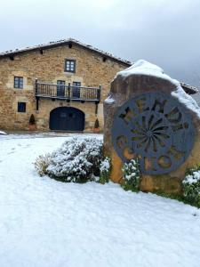 a building in the snow with a stone statue in front at MendiGoikoa Bekoa in Axpe
