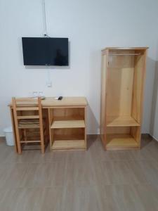 a room with a desk with a television and a cabinet at Hotel Veneza in Rio do Sul