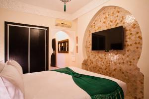 a bedroom with a bed and a tv on a wall at Villa Tilila in Marrakech