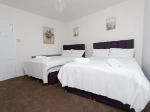 - 2 lits dans une chambre avec des draps blancs et des serviettes dans l'établissement Eastpark Residence, à Leeds