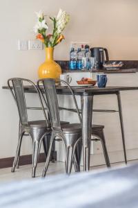 a table with two chairs and a vase with flowers at Glam Hotel Nairobi - Near Westgate Mall, Westlands in Nairobi