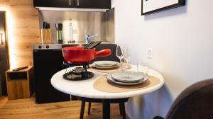 a small table with a red pot and plates on it at Wunderstay Alpine 403 Centric Studio Balcony/View in Davos