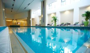 a large swimming pool in a hotel with chairs at Abacus Business & Wellness Hotel in Herceghalom