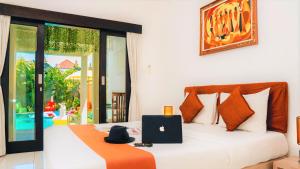 a bedroom with a bed with a laptop on it at Bahana Guest House in Kuta