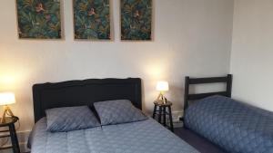 Dos camas en un dormitorio con dos lámparas y cuadros en la pared. en Gîte 5 personnes, en Fleurville