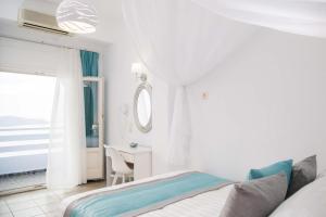 a white bedroom with a bed and a desk at Kafieris View in Firostefani