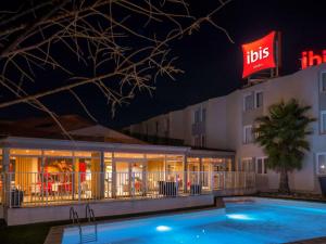 a hotel with a swimming pool in front of a building at ibis Arles in Arles