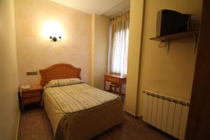 una piccola camera con letto e televisore di Hostal Restaurante Cuatro Caminos a Calera y Chozas