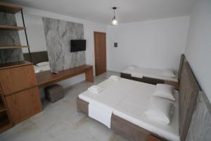 a bedroom with a large white bed and a television at Hotel Four Islands in Ksamil