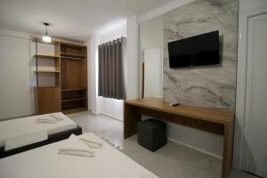 a room with two beds and a television on a wall at Hotel Four Islands in Ksamil