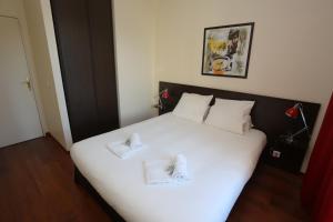 una camera da letto con un letto bianco con due asciugamani di O'Sullivans Bar and Hotel a Mandelieu La Napoule