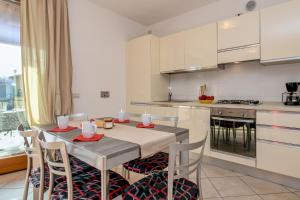 una cucina con tavolo e sedie e una cucina con armadietti bianchi di Felicity a Toscolano Maderno