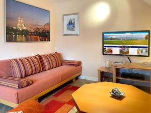 ein Wohnzimmer mit einem Sofa und einem Flachbild-TV in der Unterkunft Ferienwohnung Köln-Poll in Köln