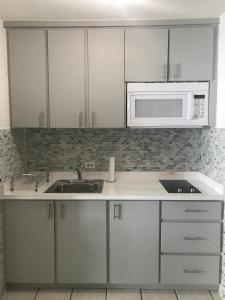 a kitchen with white cabinets and a sink and a microwave at Isla Verde Puerto Rico, Two Full Beds in San Juan