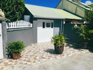 een huis met een witte deur en potplanten bij Petit Chalet in Baie-Mahault