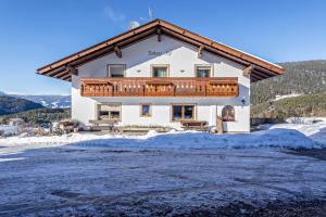 a large white house with a balcony in the snow at Aura Chalets - Nr 1 in Castelrotto