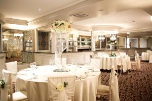 a banquet room with white tables and white chairs at Mulroy Woods Hotel in Milford