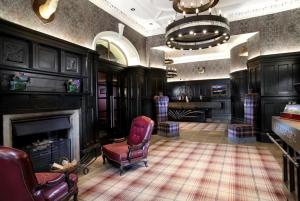 Loch Lomond Lodge في بالوتش: غرفة معيشة بها موقد وكرسي احمر