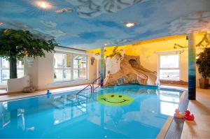 een zwembad in een kamer met een plafond bedekt met wolken bij Smileys Fluss Chalet in Trebesing