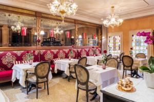 un restaurant avec des tables, des chaises et des lustres blancs dans l'établissement Hotel Moresco, à Venise
