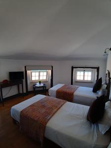 a hotel room with two beds and a television at Hotel Ribamar in Nazaré