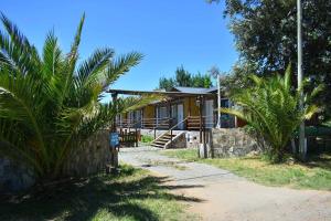 a house with palm trees in front of it at Cabañas Dolce Far Niente in Tandil