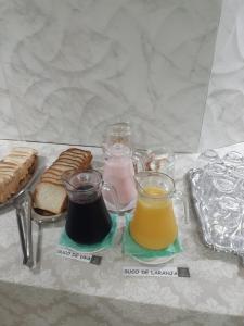 a table with a tray of bread and two glasses of juice at Hotel Veneza in Rio do Sul
