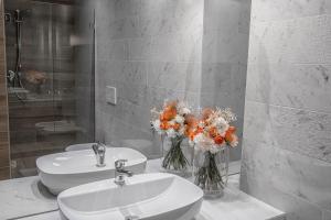 a bathroom with two sinks and flowers in vases at AmbientHotels Panoramic in Rimini